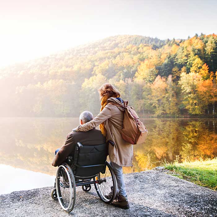 Eine Hospizbegleiterin begleitet einen Rollstuhlfahrer